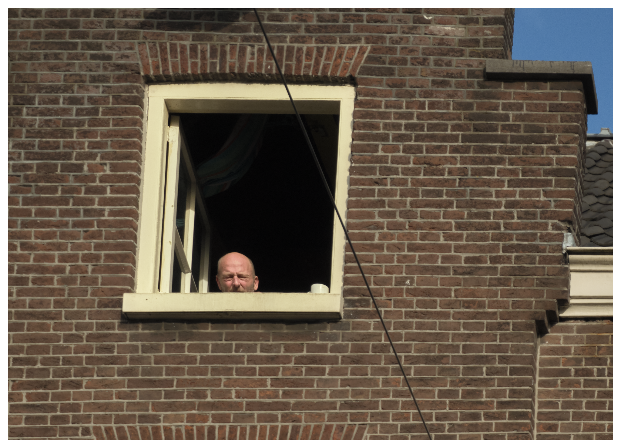 Man geniet van de laatste zonnestralen op de vierde verdieping, Jordaan